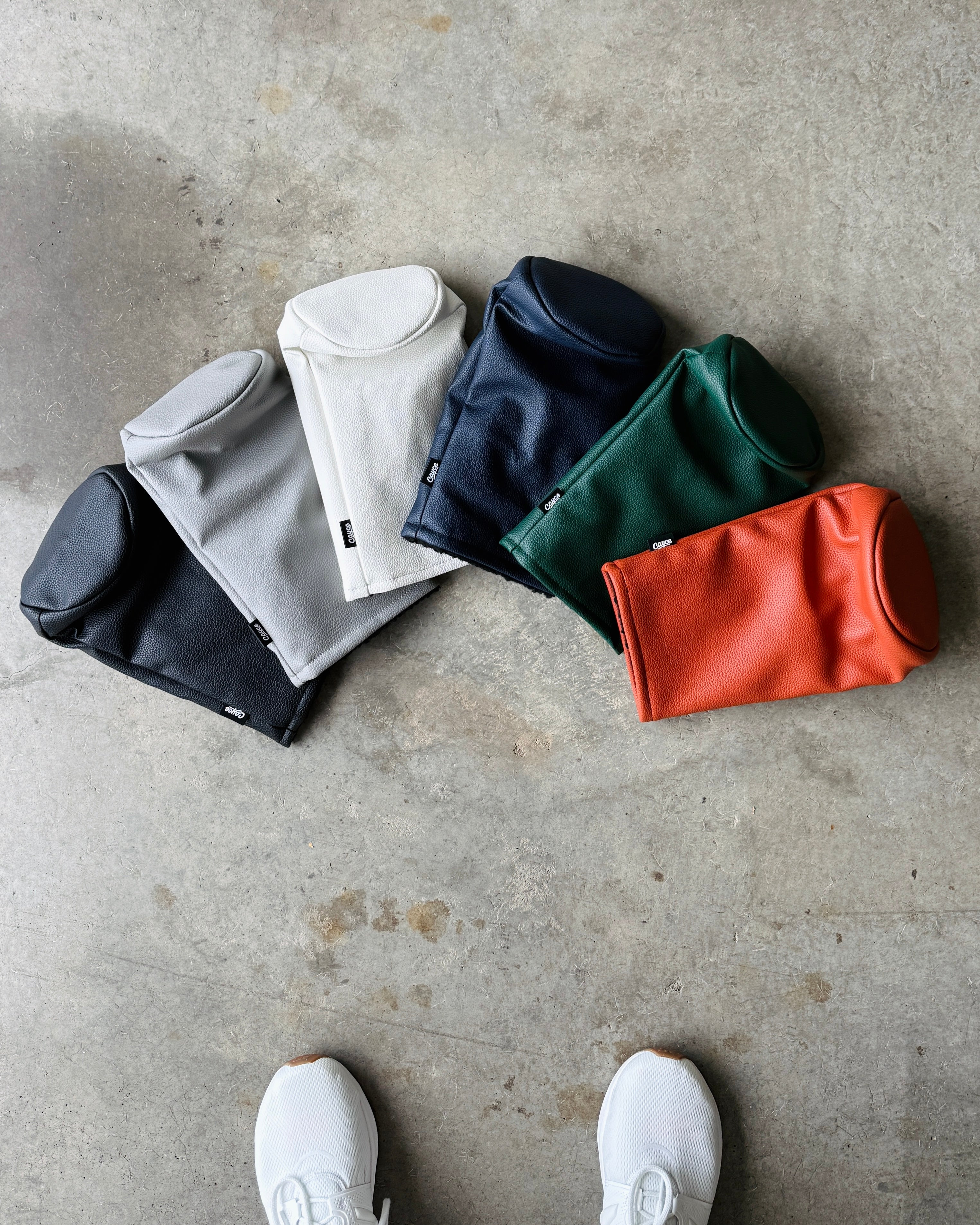 solid color golf headcovers laying on the ground