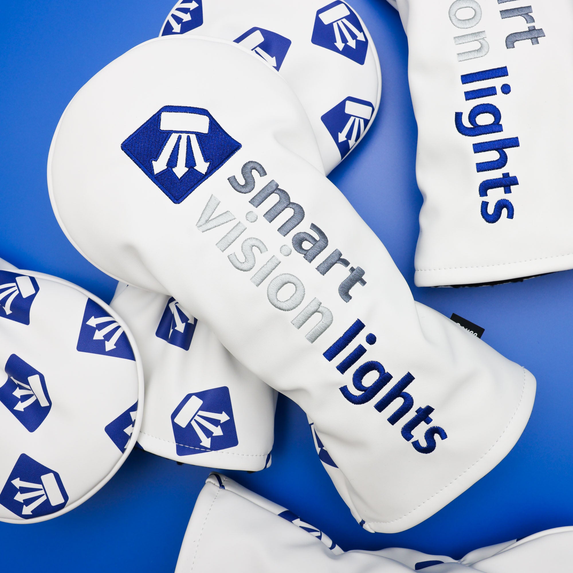 custom embroidered driver headcovers scattered on a blue backdrop from cayce golf