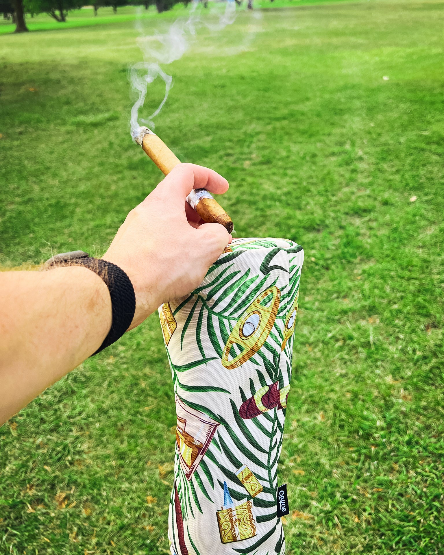 golfer smoking a cigar while holding his cigar driver head cover on the course