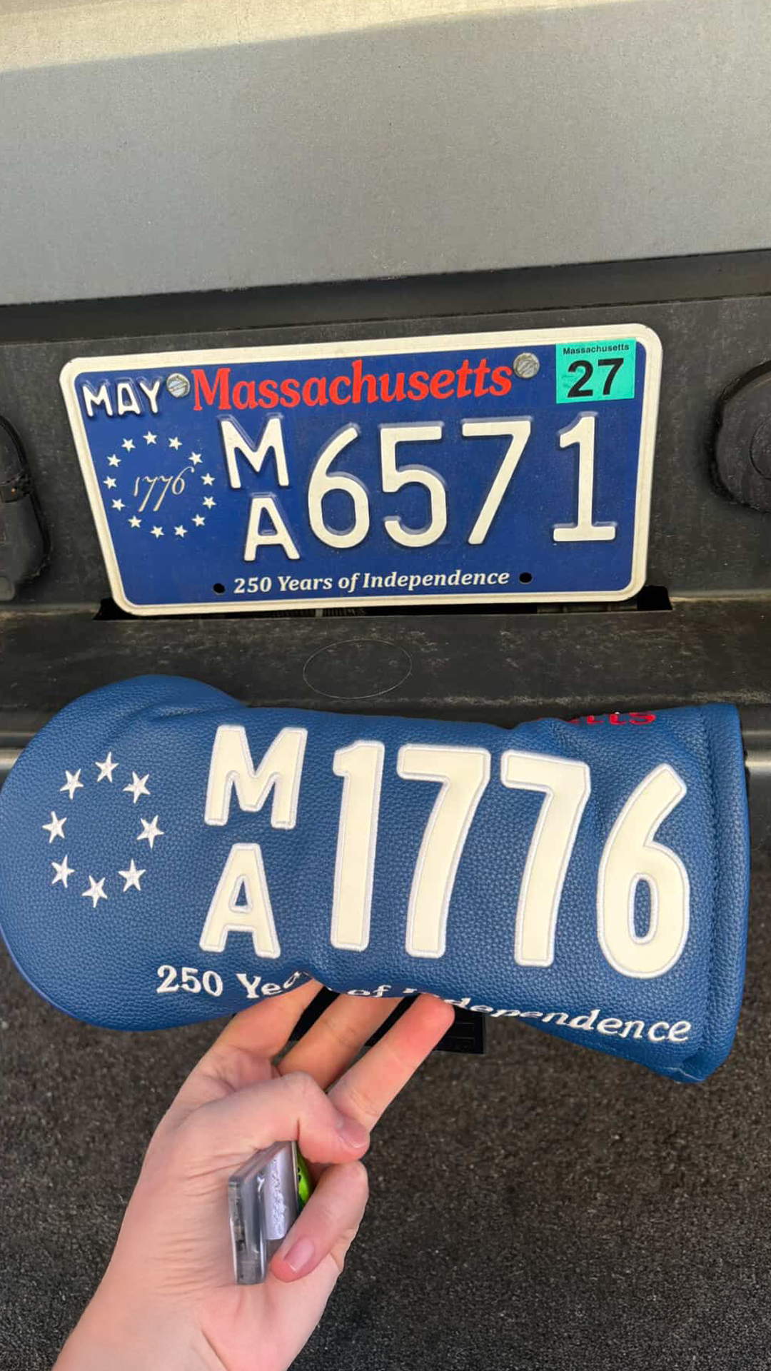 Golfer holding their blue 1776 Massachusetts Anniversary golf headcover next to their license plate