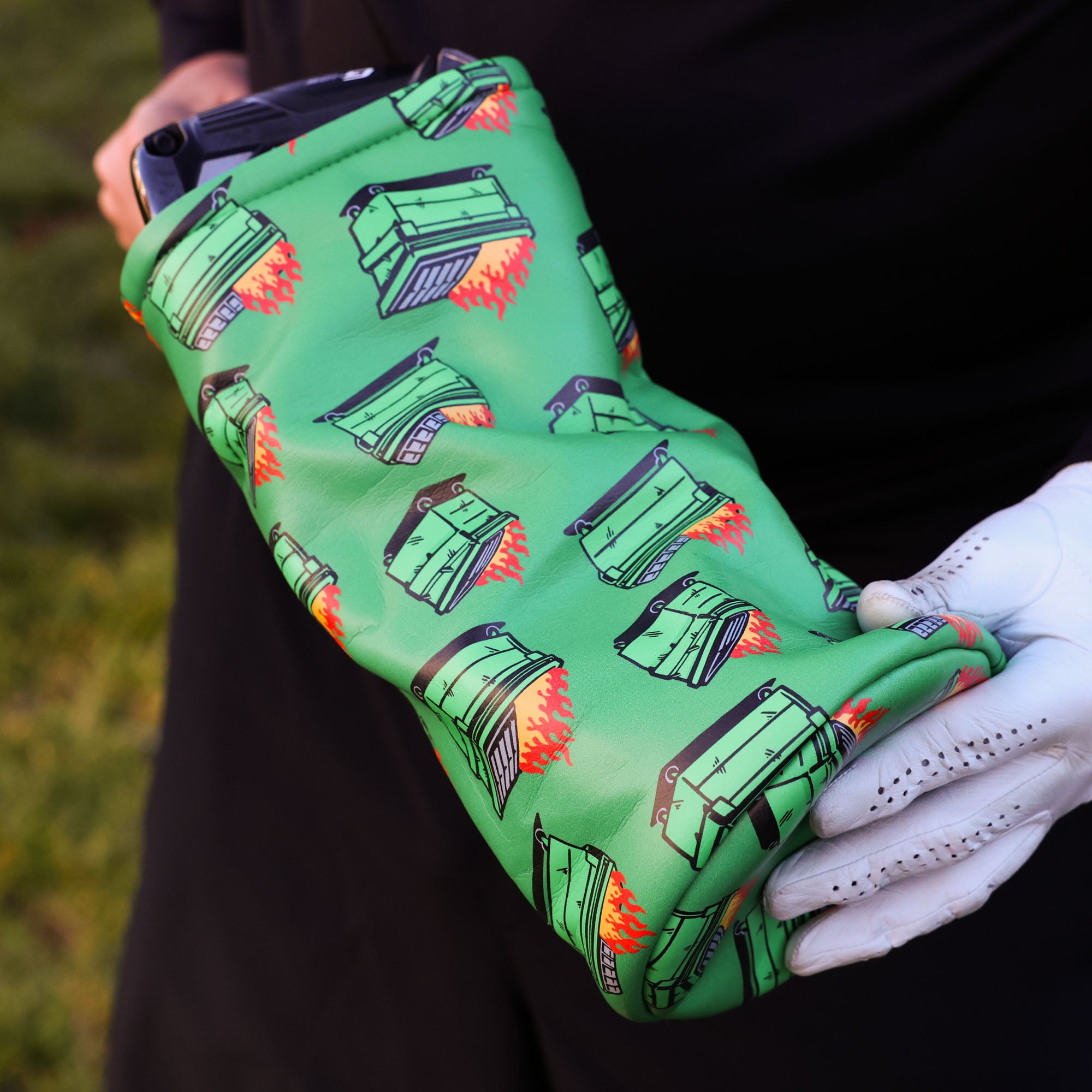 golfer pulling a dumpster fire driver head cover off of his driver getting ready to hit their tee shot