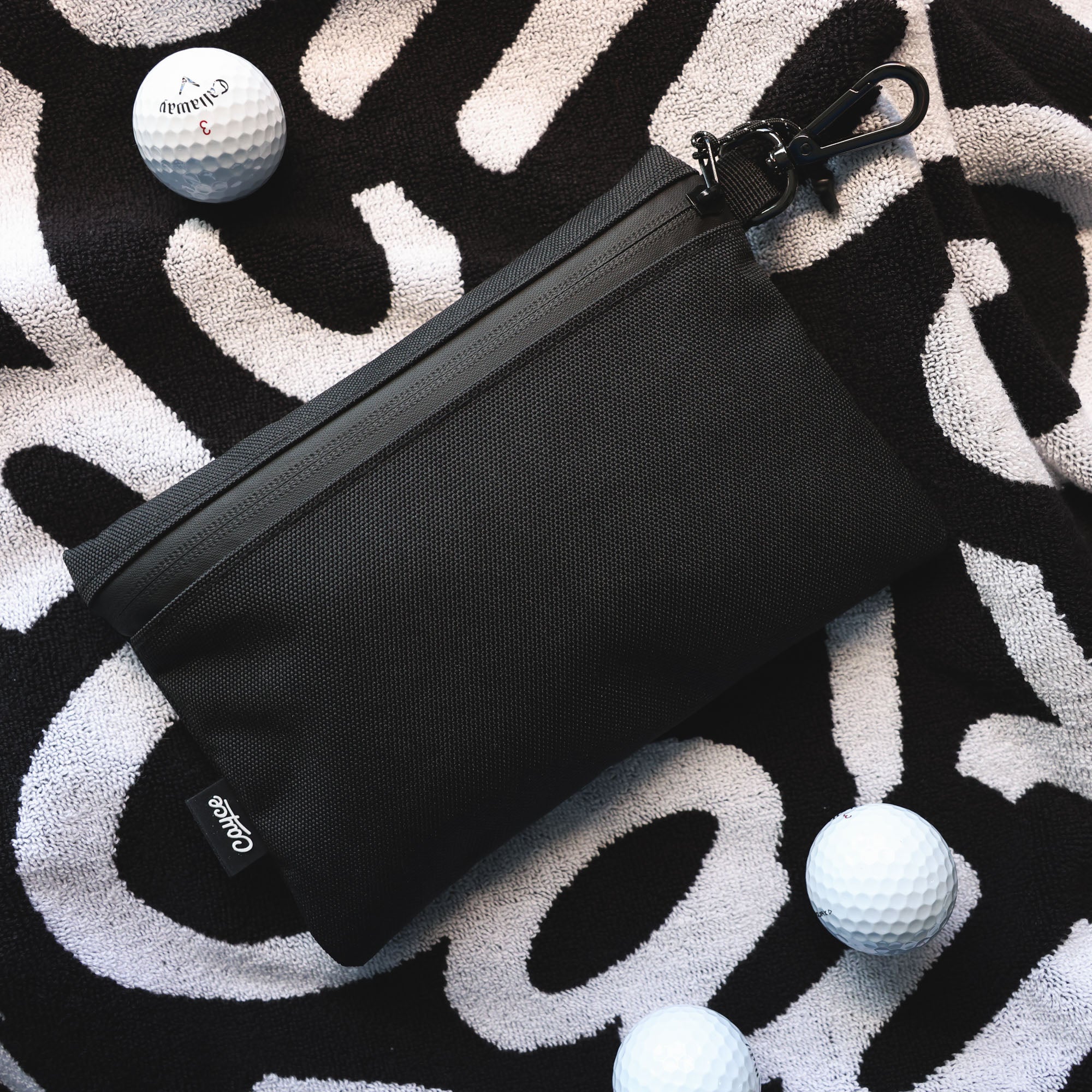 golf valuables pouch sitting on a golf towel with golf balls