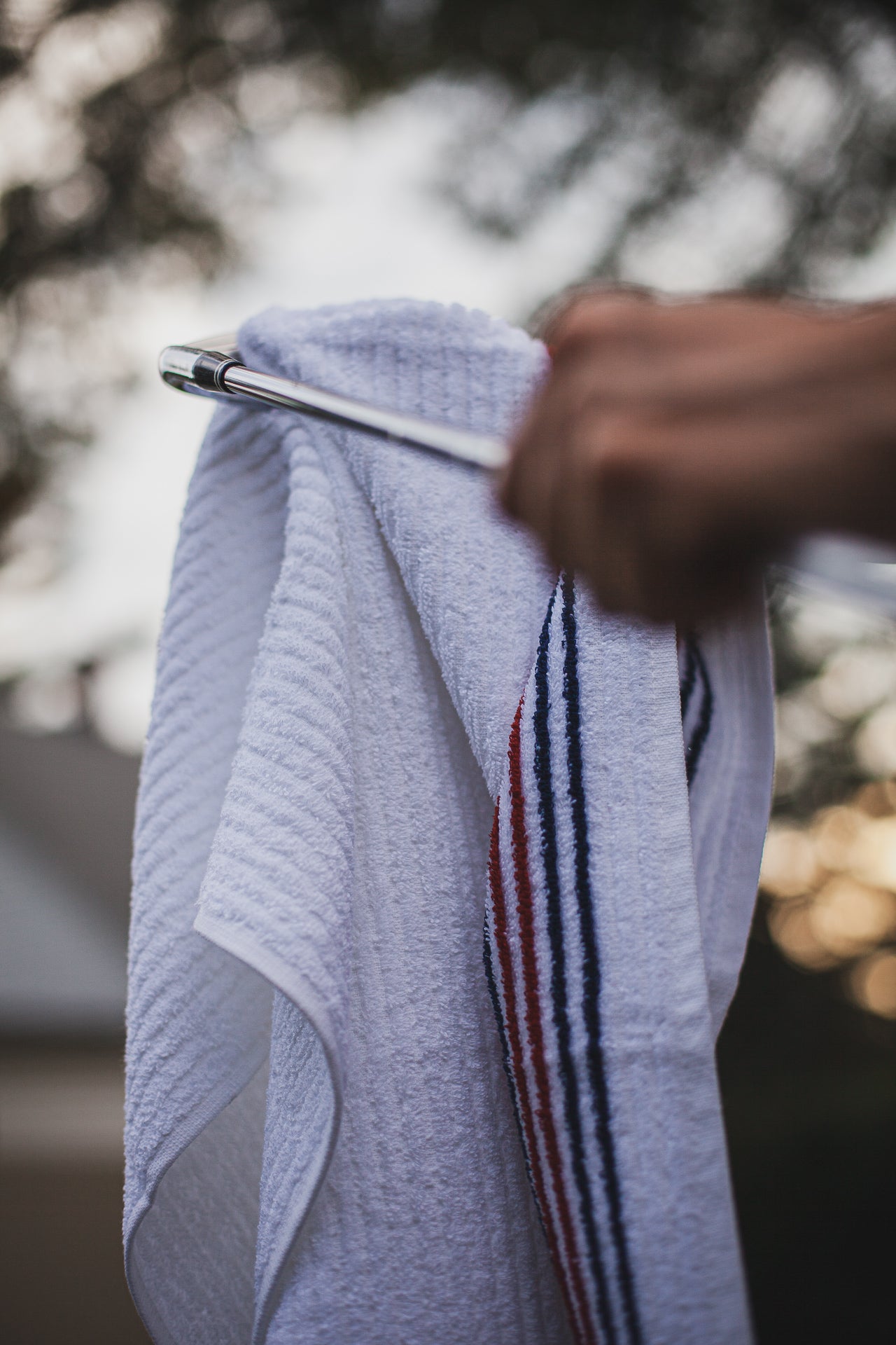 Golfer using our Red + Navy Caddy Towel to clean their golf club 